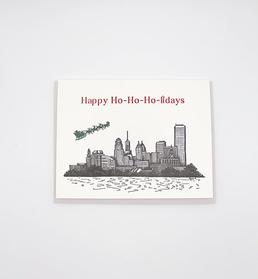 Letterpress card with city skyline and Santa/ reindeer flying over that reads Happy Ho-Ho-Ho-lidays" by Rust Belt Love.