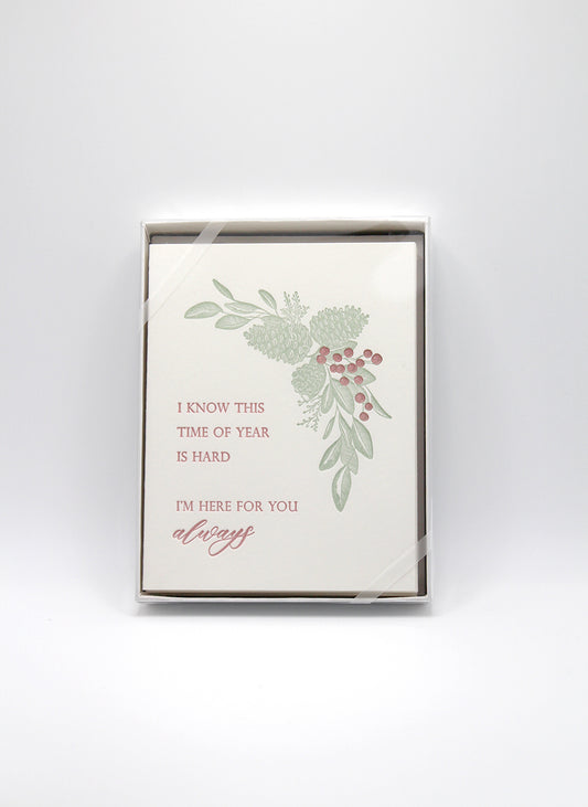 Box of letterpress holiday cards with pinecones that says " I Know This Time Of Year Is Hard I'm Here For You Always" by Rust Belt Love