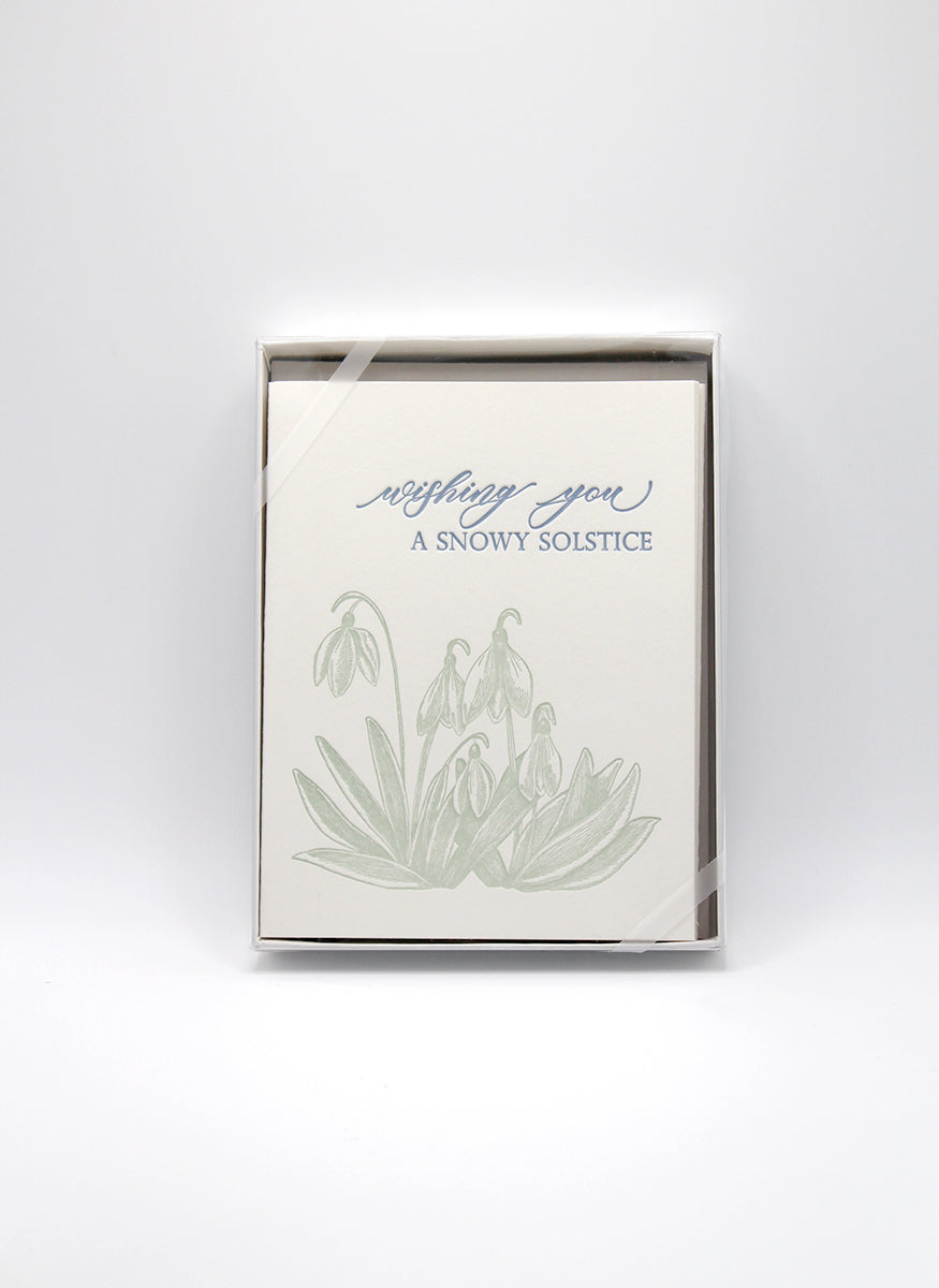 Box of letterpress holiday cards with green florals that reads "wishing you a snowy solstice" by Rust Belt Love