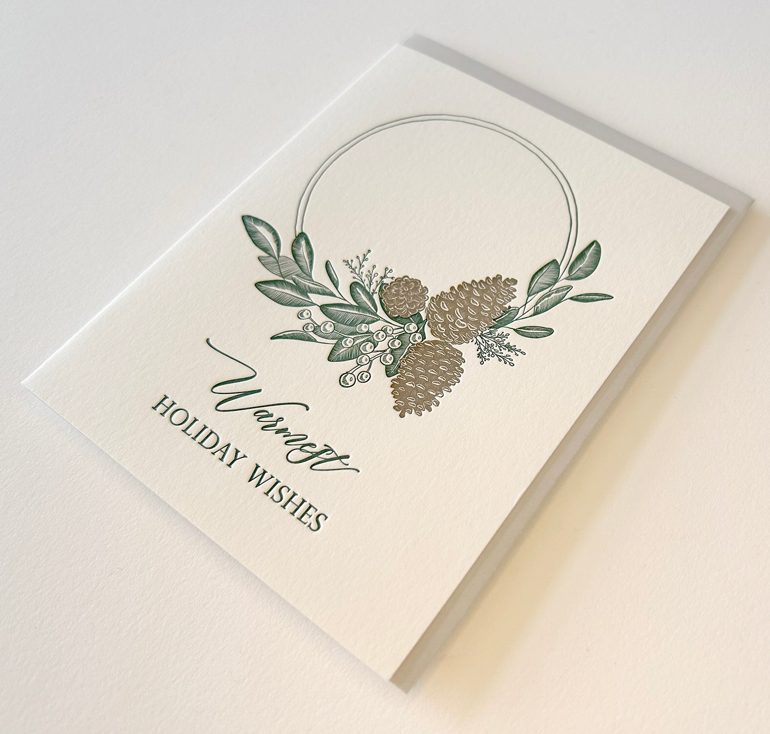 Letterpress holiday card with pinecones and greenery that says "Warmest holiday wishes" by Rust Belt Love